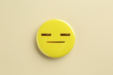 Image of Badge with distrustful or sleepy face on beige background