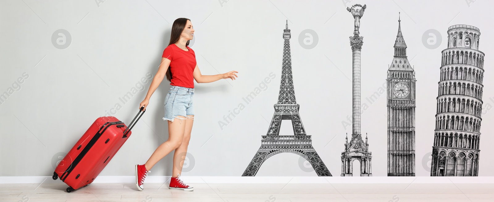 Image of Happy traveler with suitcase walking towards illustration of famous landmarks on light grey wall. Banner design