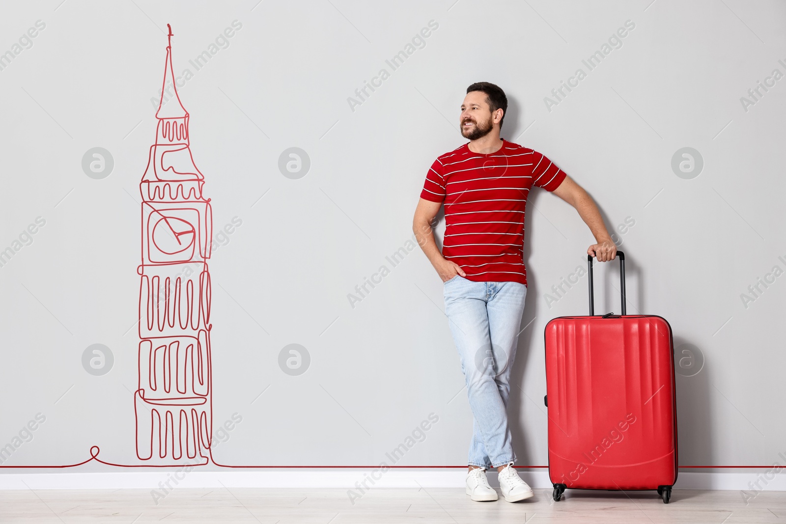 Image of Happy traveler with suitcase looking at illustration of Big Ben on light grey wall