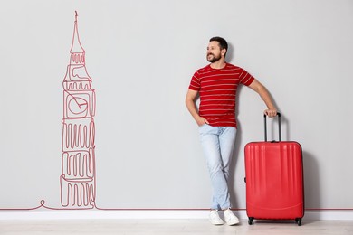 Image of Happy traveler with suitcase looking at illustration of Big Ben on light grey wall