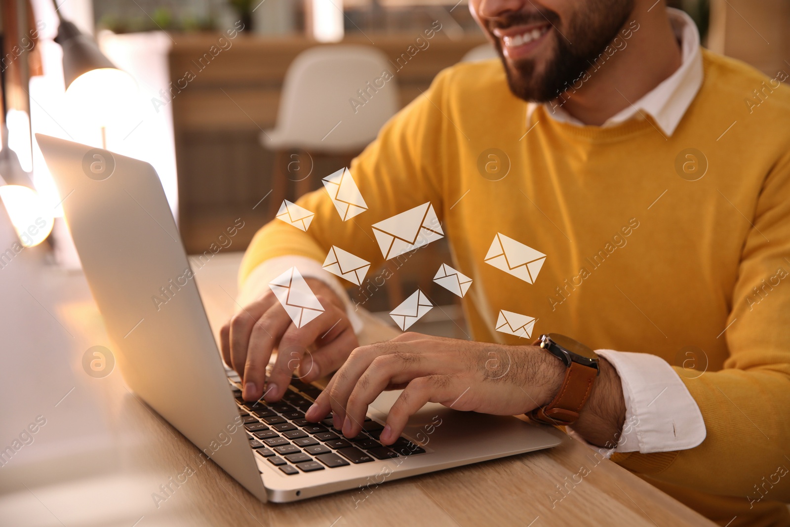 Image of Man using laptop at table, closeup. Envelopes as symbol of message over computer