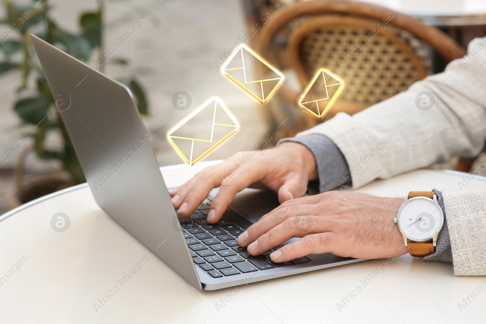 Image of Man using laptop at table, closeup. Envelopes as symbol of message over computer