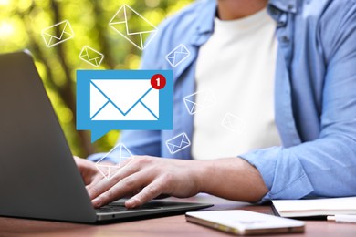 Image of Man using laptop at table, closeup. Envelopes as symbol of message over computer