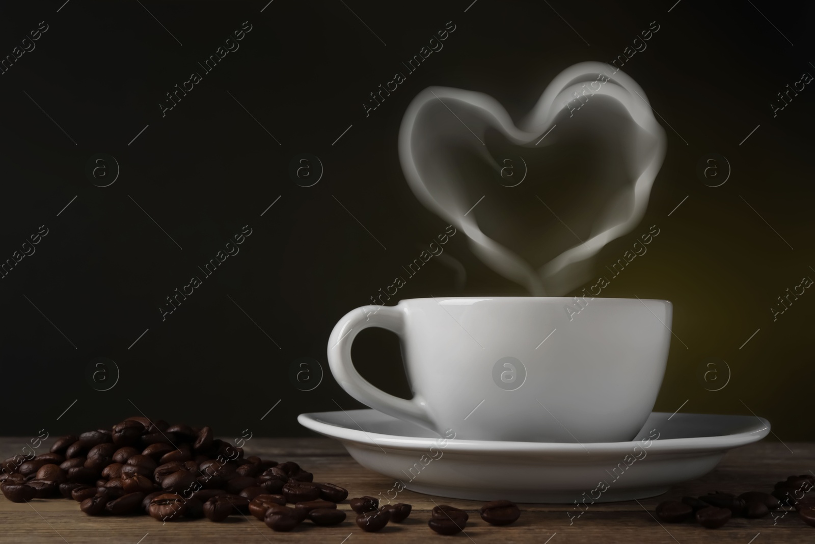 Image of Fresh aromatic coffee and beans on wooden table, space for text. Steam in shape of heart over cup