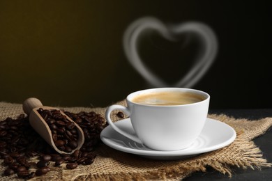 Image of Fresh aromatic coffee and beans on table, space for text. Steam in shape of heart over cup