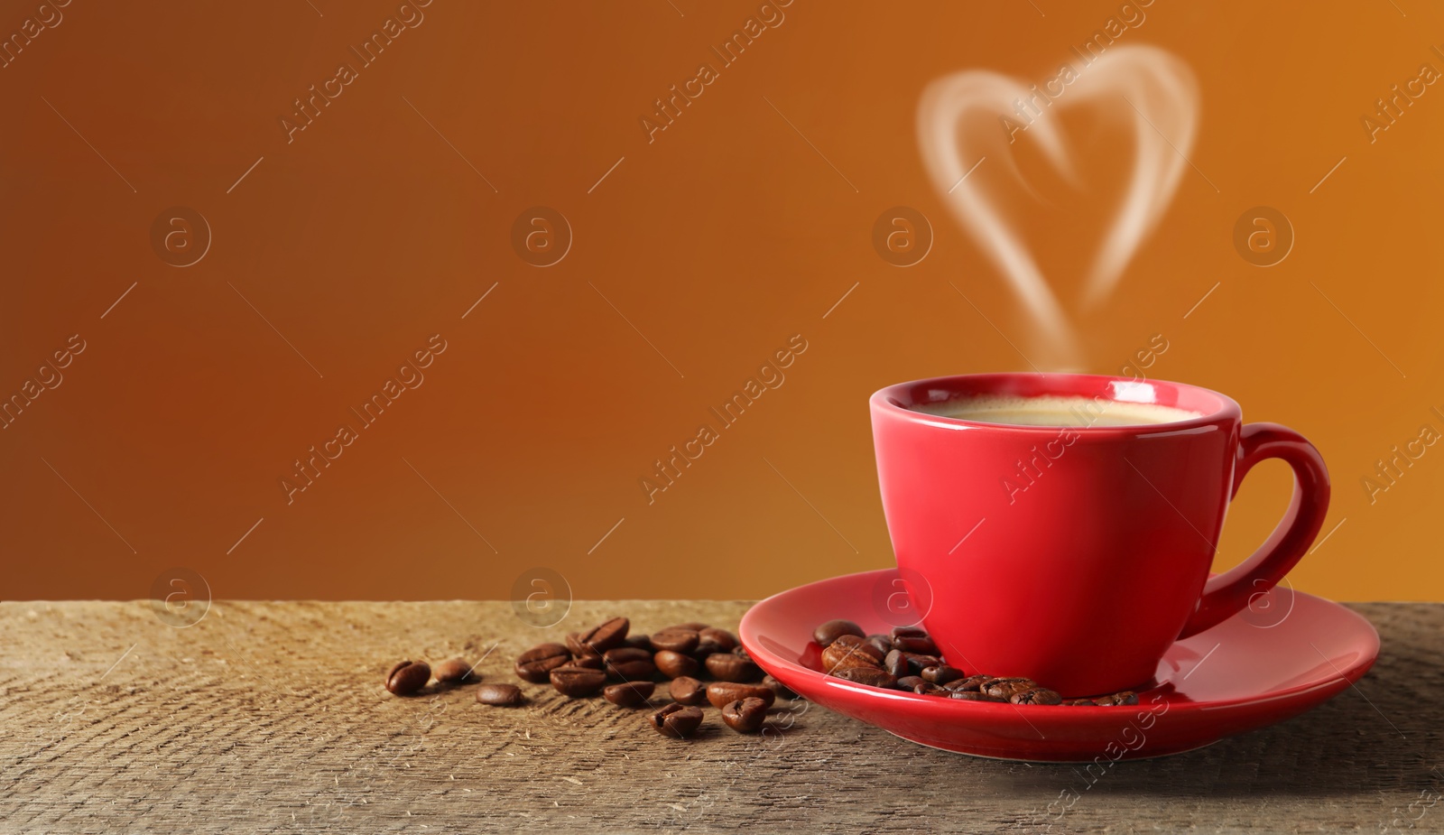 Image of Fresh aromatic coffee and beans on wooden table, space for text. Steam in shape of heart over cup