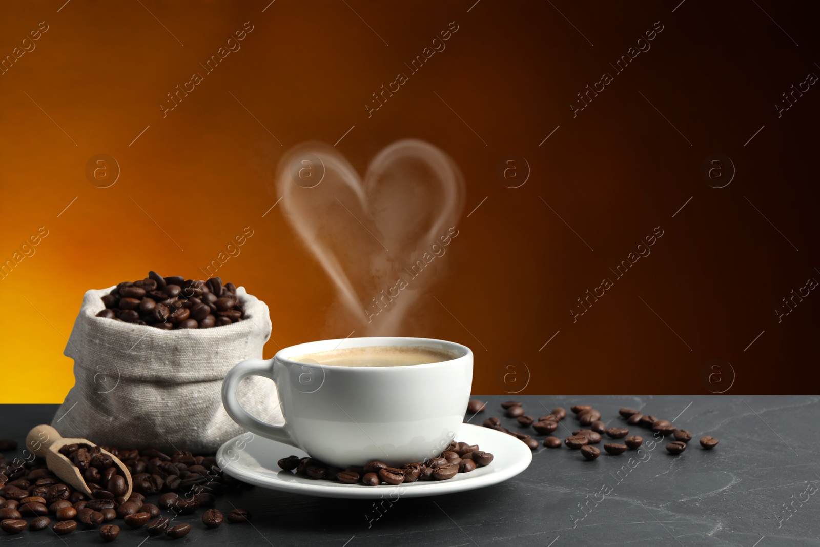 Image of Fresh aromatic coffee and beans on table, space for text. Steam in shape of heart over cup