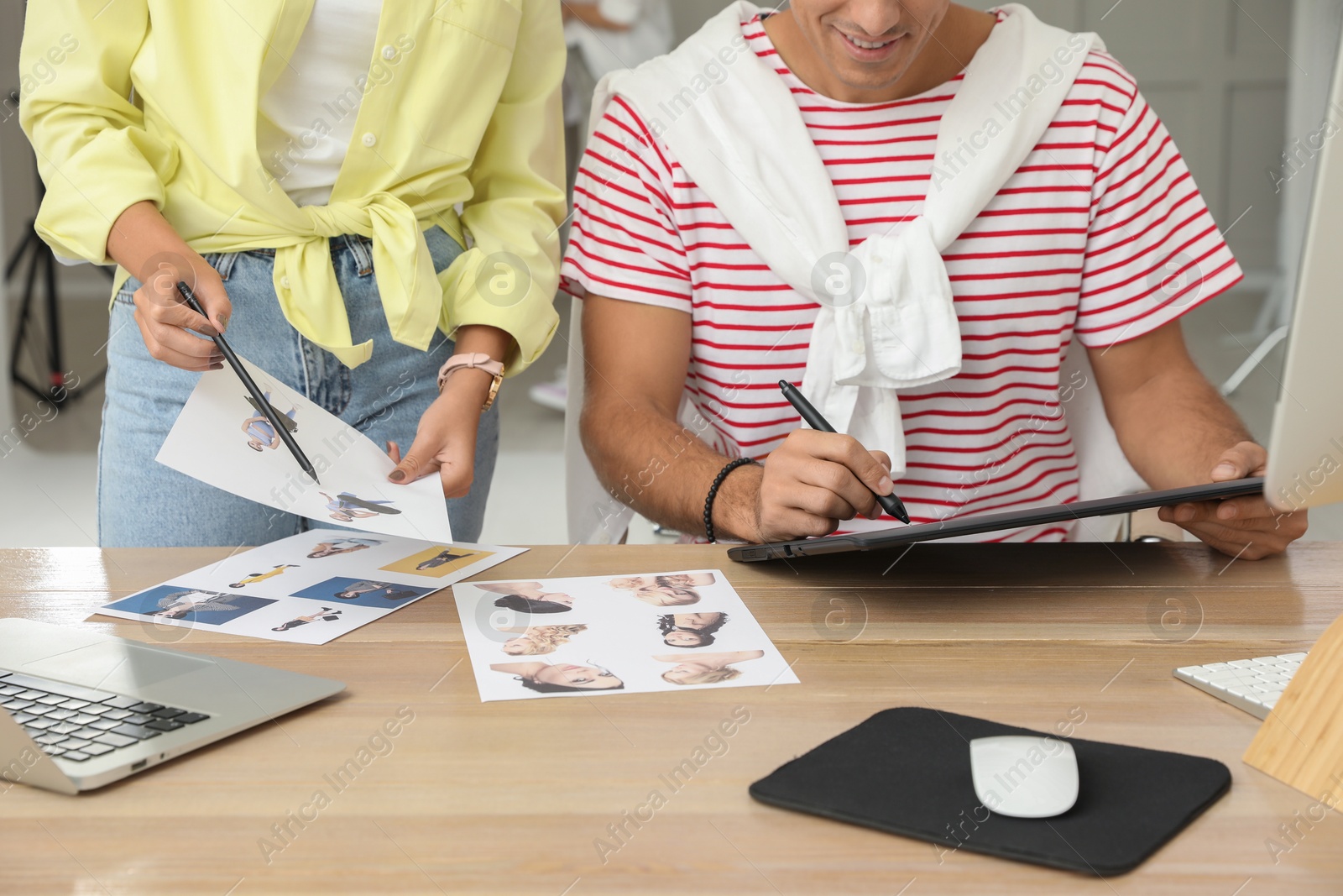 Photo of Professional retoucher with colleague working at desk in photo studio, closeup