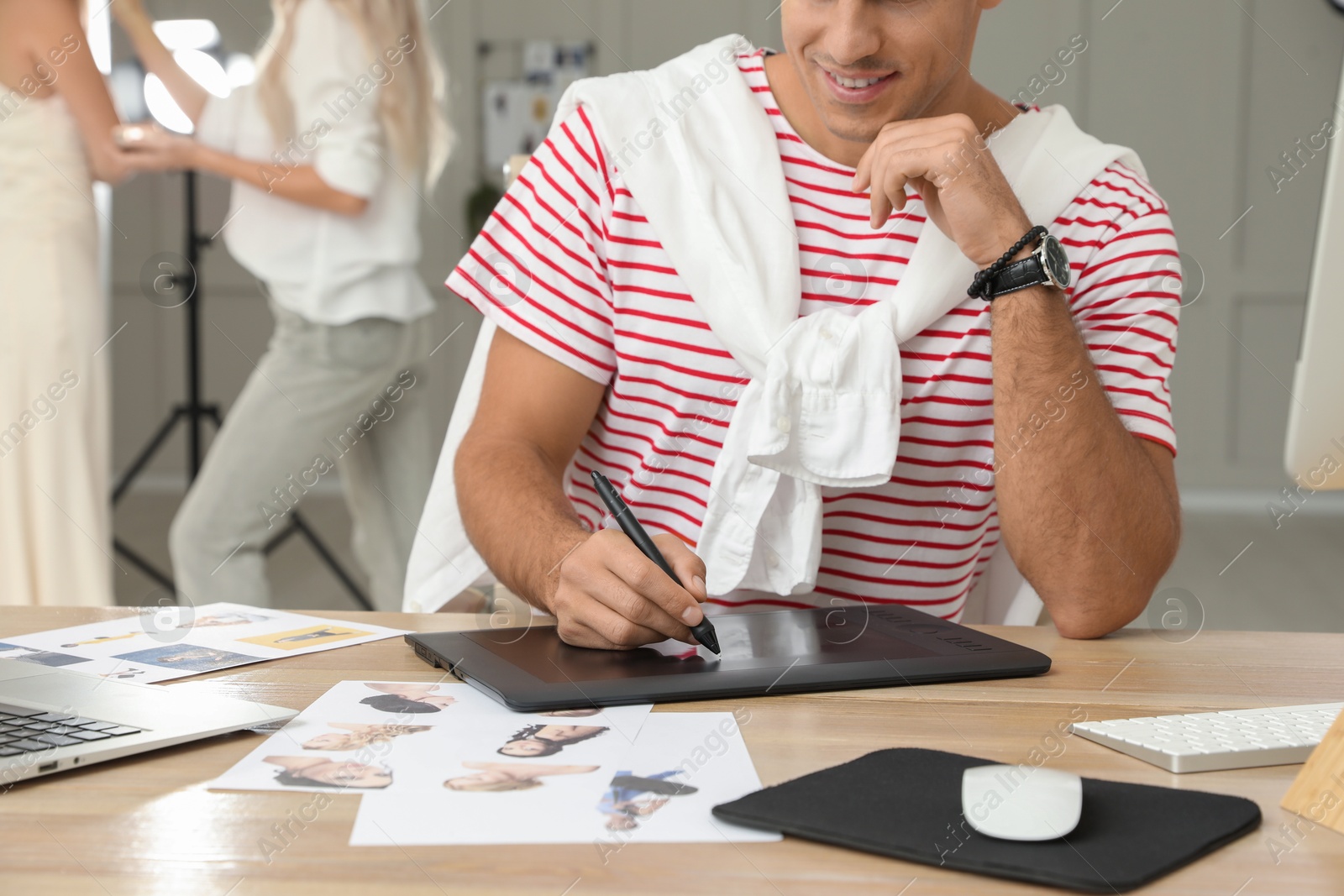 Photo of Professional retoucher working with graphic tablet at desk in photo studio, closeup