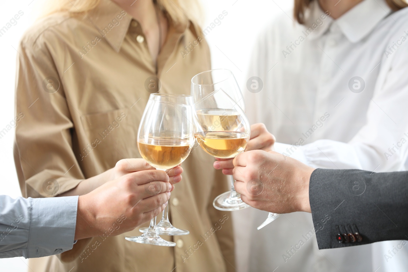 Photo of People clinking glasses of wine indoors, closeup