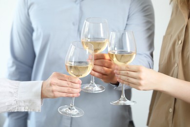 People clinking glasses of wine indoors, closeup