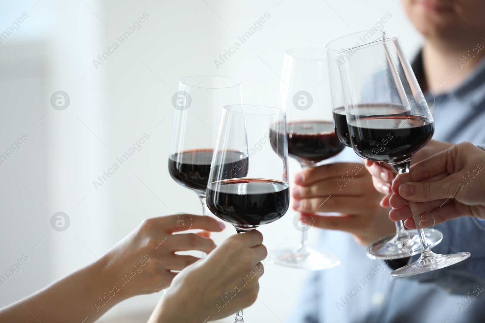 Photo of People clinking glasses of wine indoors, closeup