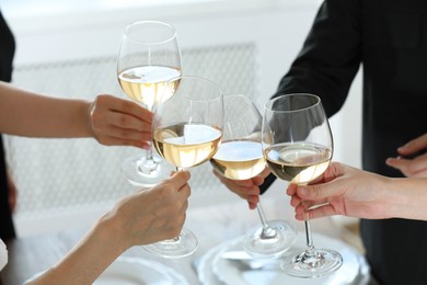 People clinking glasses of wine indoors, closeup