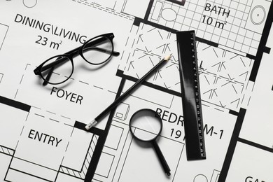 Photo of Ruler, glasses, magnifying glass and pencil on different architectural drawings, top view