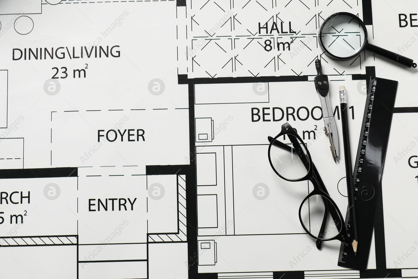 Photo of Ruler, glasses, dividers, magnifying glass and pencil on different architectural drawings, top view