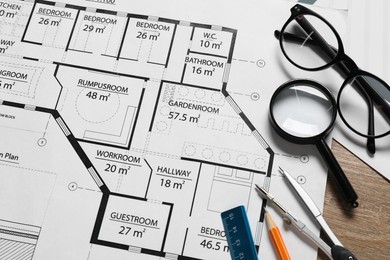 Photo of Different architectural drawings, pencil, dividers, ruler, glasses and magnifying glass on wooden table, top view