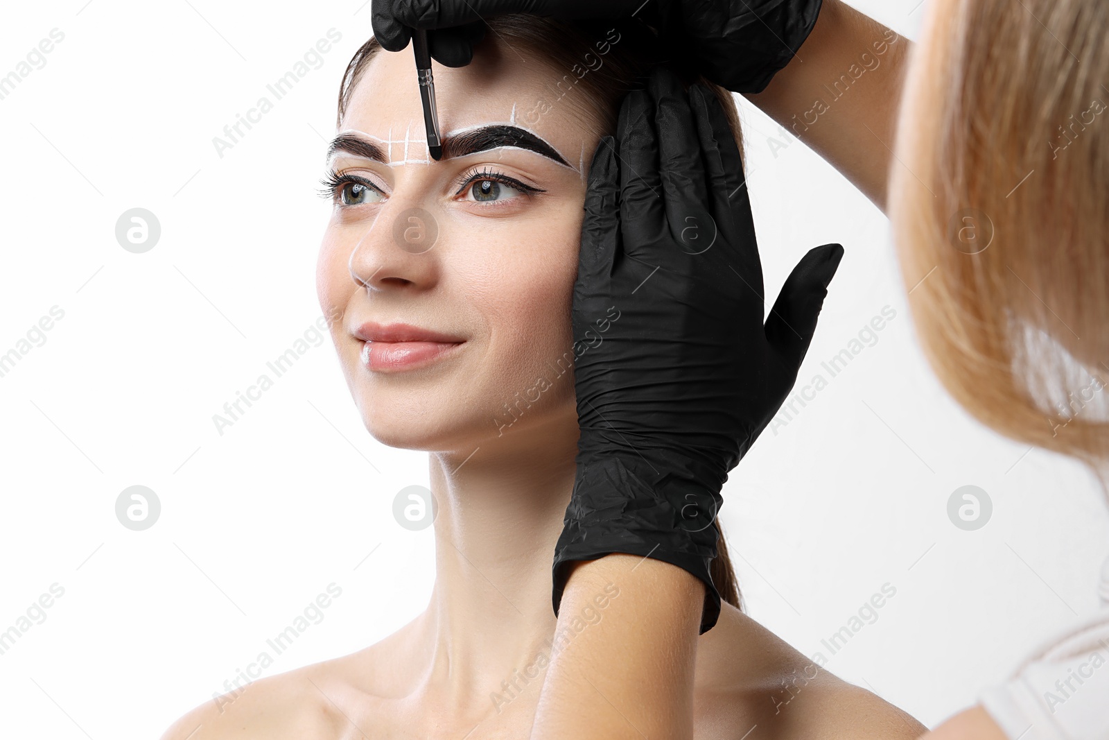 Photo of Young woman undergoing henna eyebrows dyeing procedure on white background