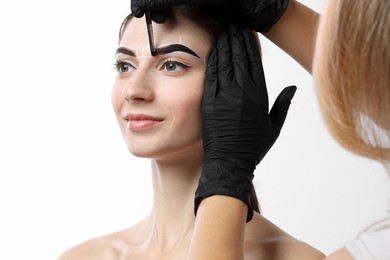 Photo of Young woman undergoing henna eyebrows dyeing procedure on white background