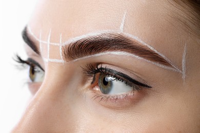 Young woman during henna eyebrows dyeing procedure on white background, closeup