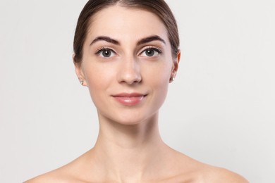 Photo of Beautiful young woman after henna eyebrows dyeing on light background, closeup