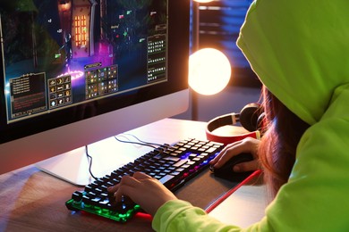 Photo of Girl playing video game with keyboard and mouse at table indoors