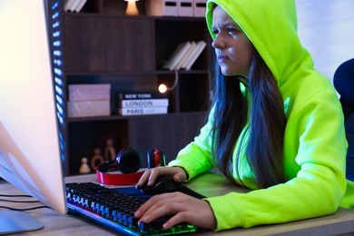 Photo of Girl playing video game with keyboard and mouse at table indoors