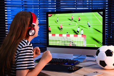 Photo of Football fan watching game live stream at table with computer keyboard, smartphone, mouse and soccer ball