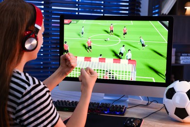 Photo of Football fan watching game live stream at table with computer keyboard, mouse, soccer ball and monitor