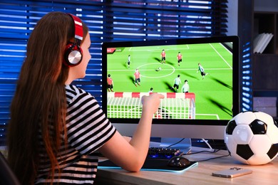 Photo of Football fan watching game live stream at table with computer keyboard, smartphone, mouse and soccer ball