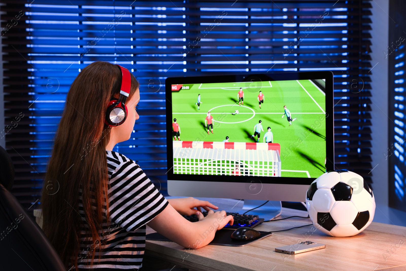 Photo of Girl playing video game with keyboard at table indoors