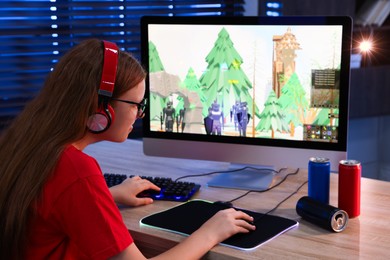 Girl playing video game with keyboard and mouse at table in dark room