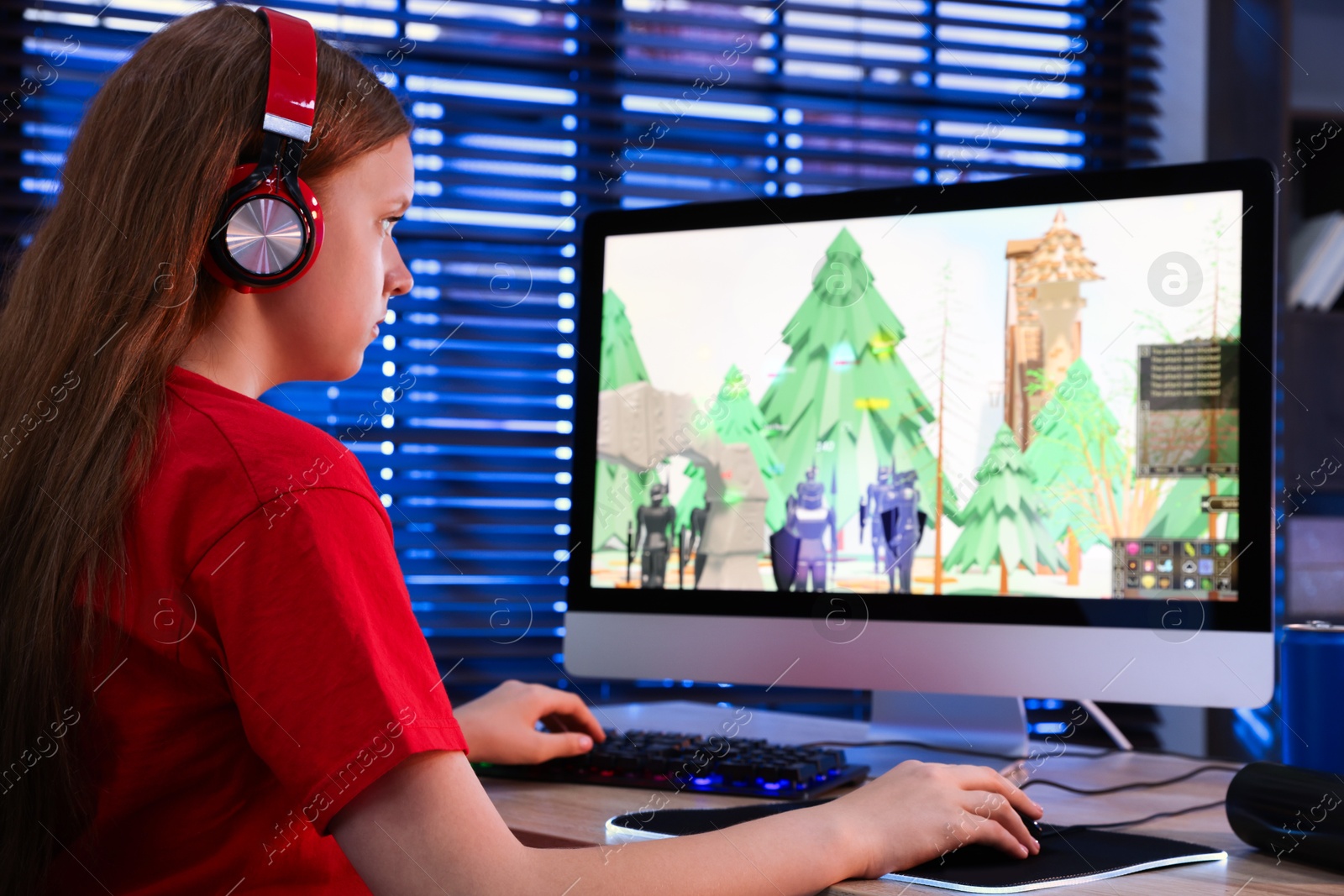 Photo of Girl playing video game with keyboard and mouse at table in dark room