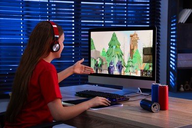 Girl playing video game with keyboard and mouse at table in dark room