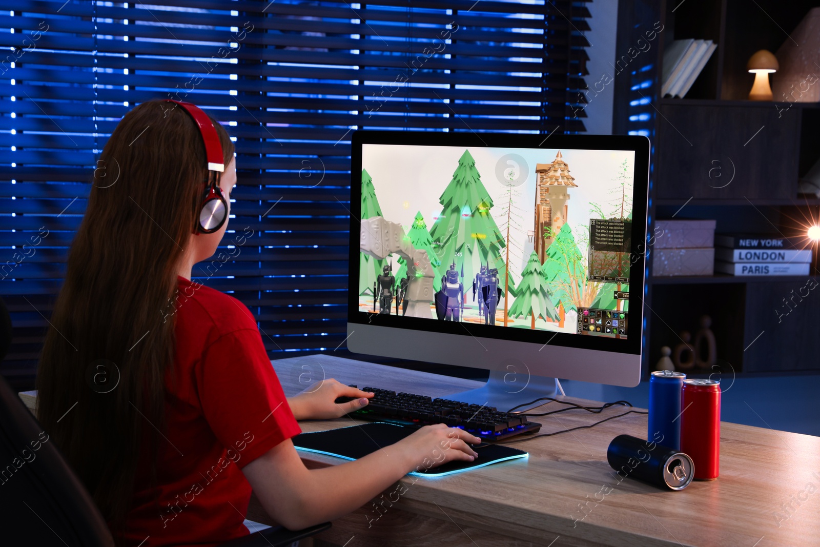 Photo of Girl playing video game with keyboard and mouse at table in dark room