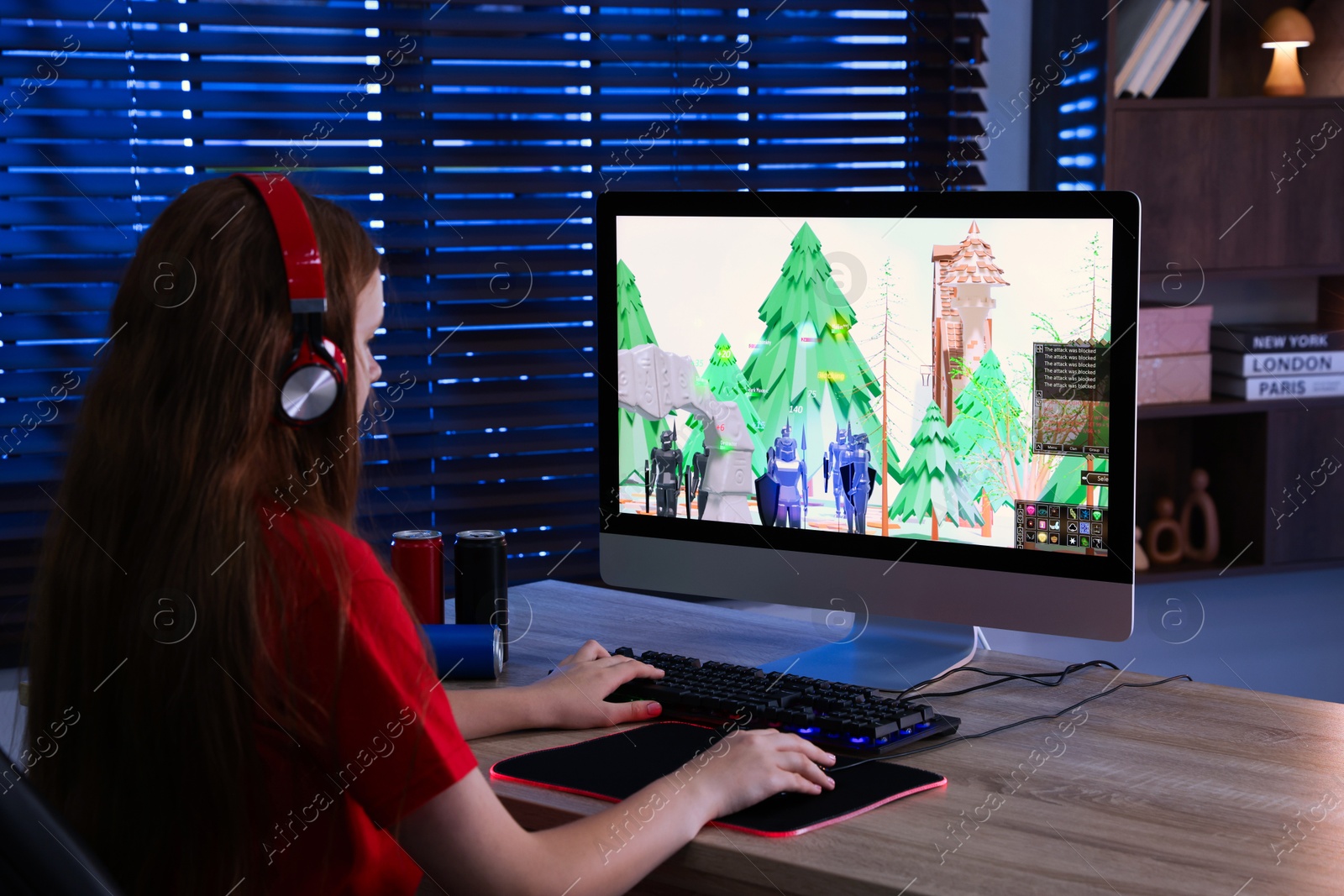 Photo of Girl playing video game with keyboard and mouse at table in dark room