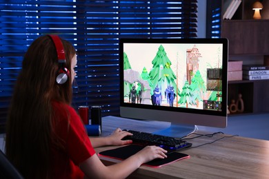 Girl playing video game with keyboard and mouse at table in dark room