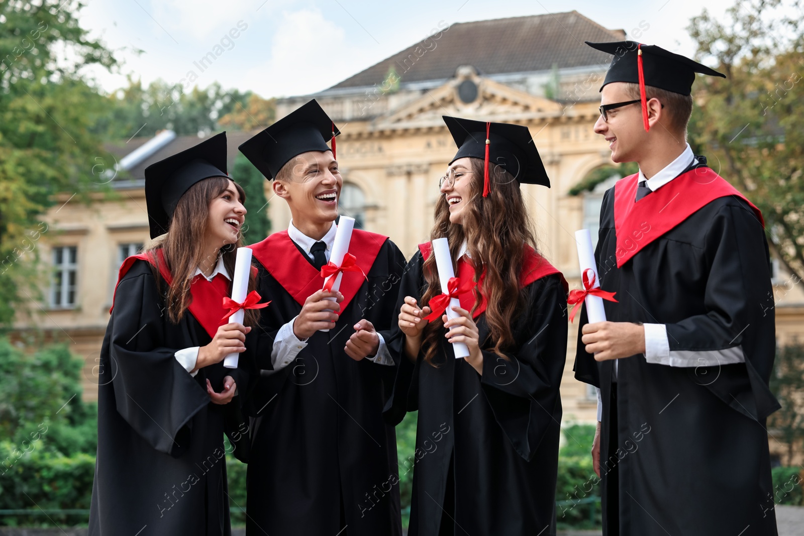 Photo of Happy students with diplomas after graduation ceremony outdoors