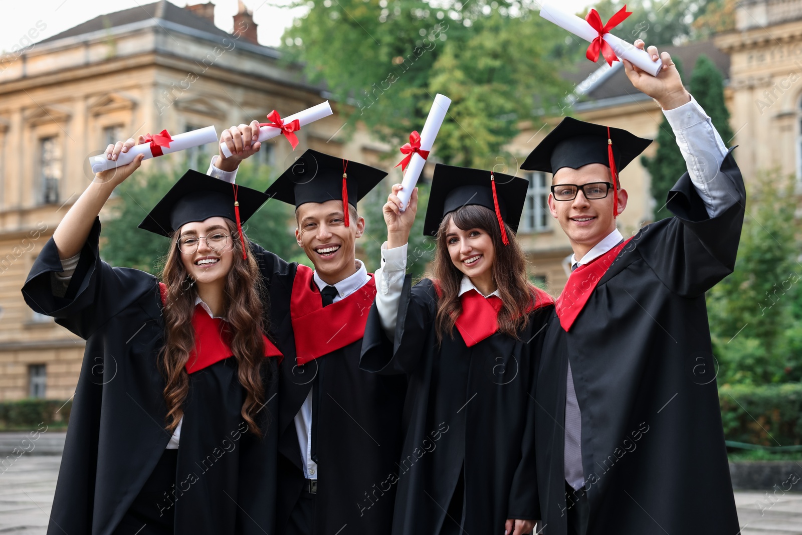 Photo of Happy students with diplomas after graduation ceremony outdoors