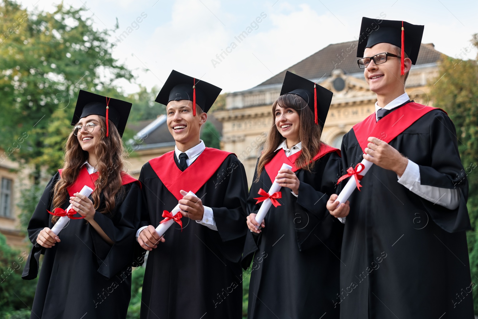 Photo of Happy students with diplomas after graduation ceremony outdoors