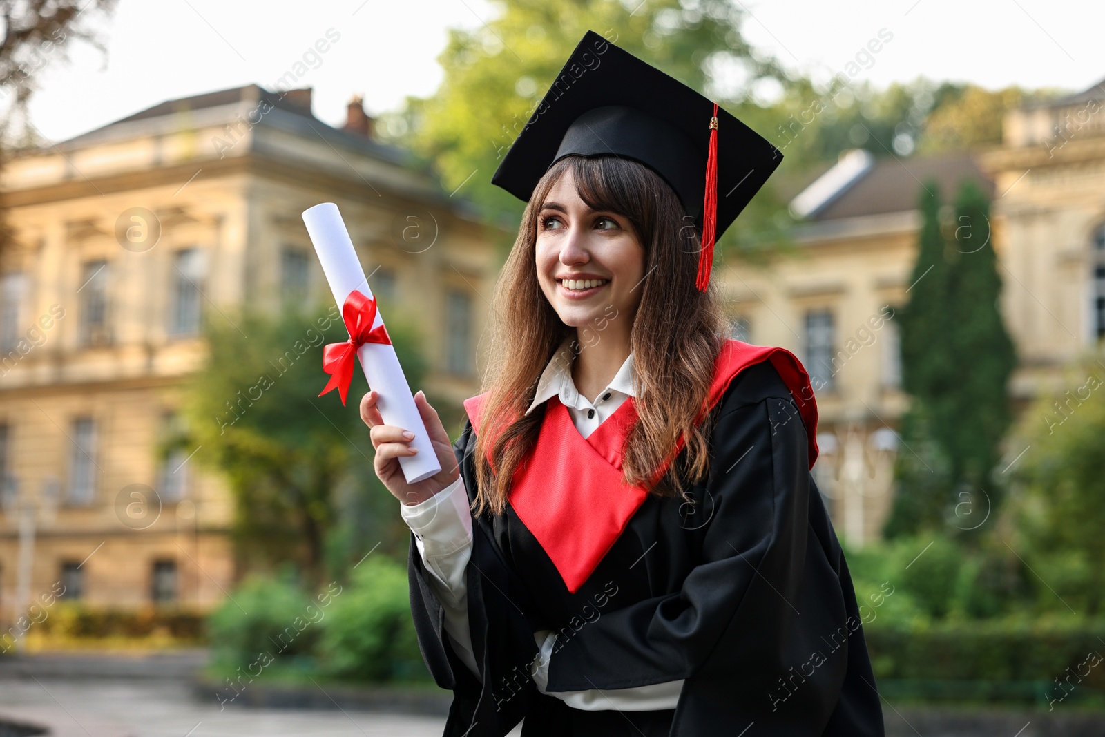 Photo of Happy student with diploma after graduation ceremony outdoors