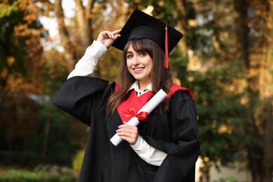 Photo of Happy student with diploma after graduation ceremony outdoors