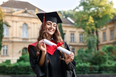 Photo of Happy student with diploma after graduation ceremony outdoors