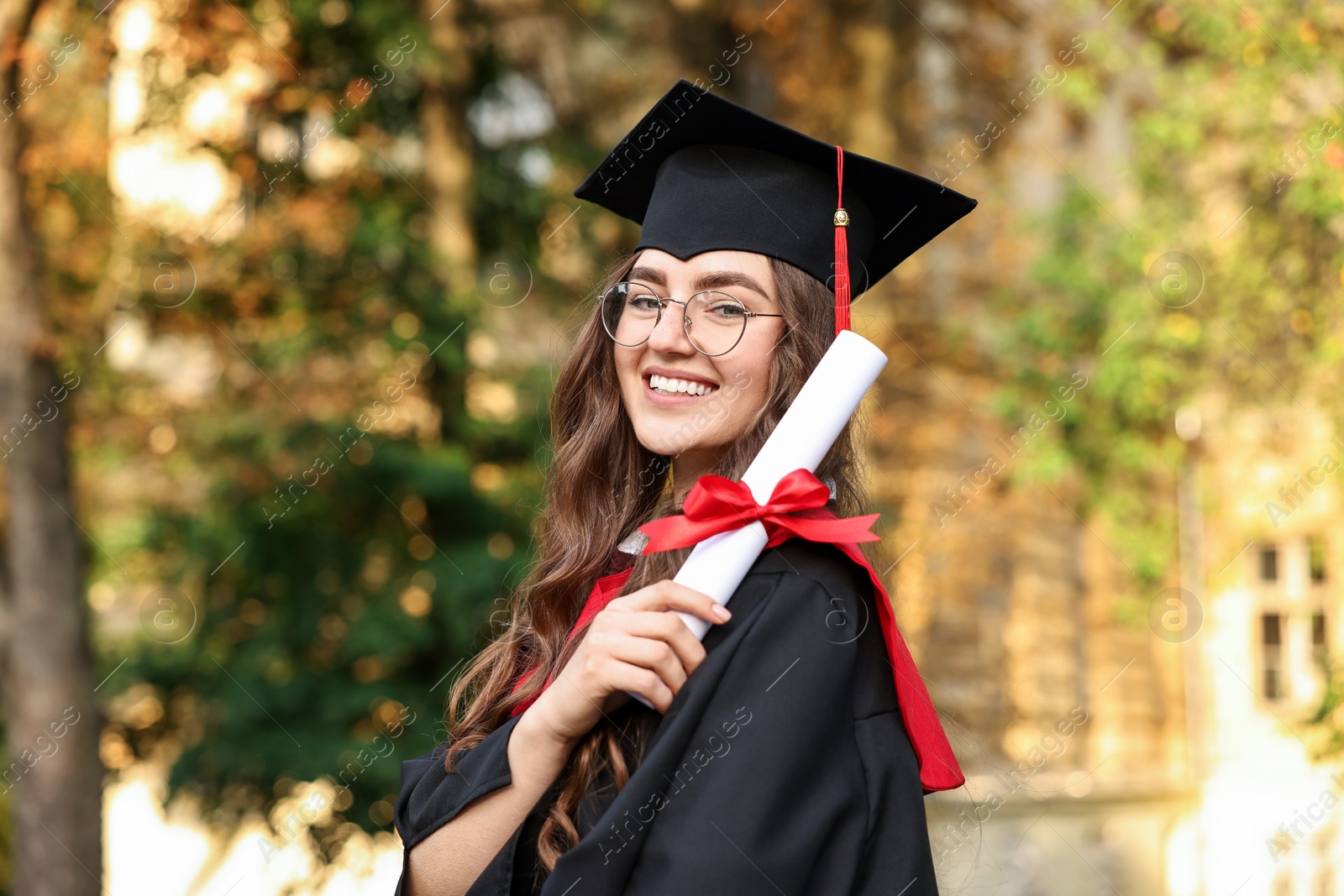 Photo of Happy student with diploma after graduation ceremony outdoors