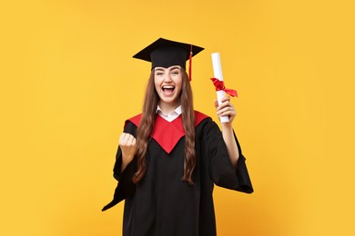 Photo of Happy student with diploma after graduation on orange background