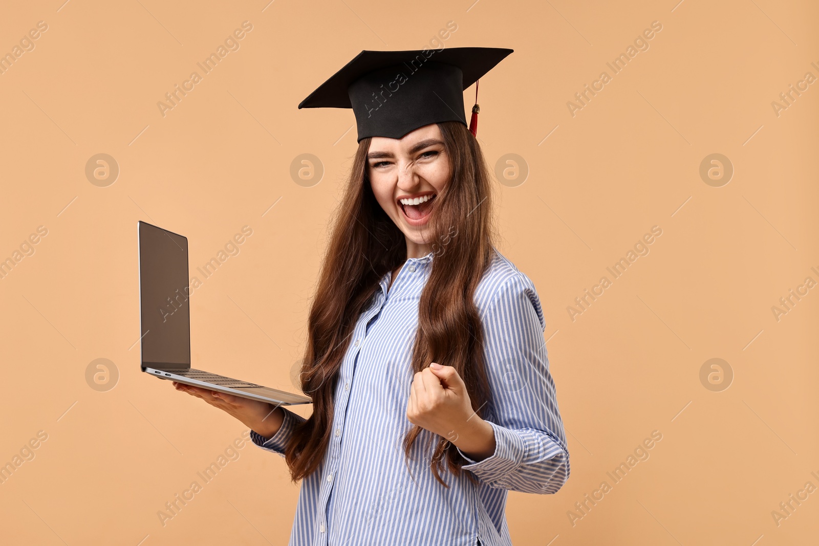 Photo of Happy student with laptop after graduation on beige background