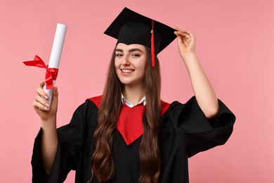 Photo of Happy student with diploma after graduation on pink background