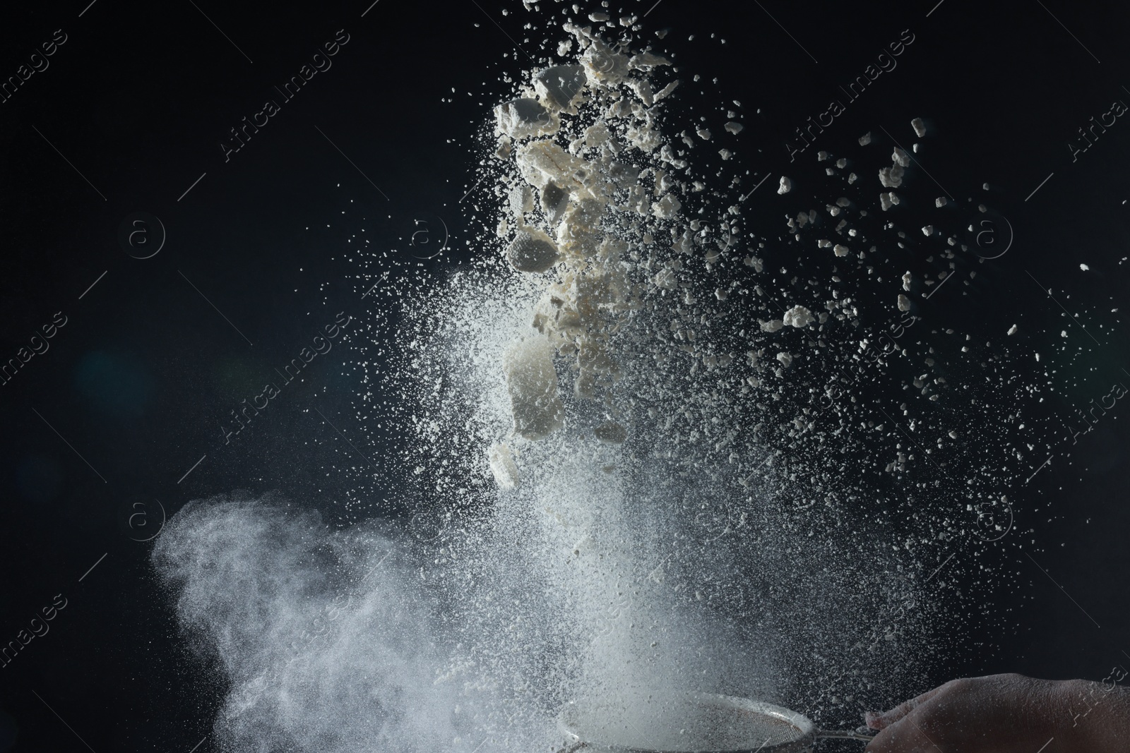 Photo of Woman throwing flour from sieve on black background, closeup