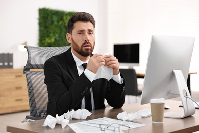 Photo of Sick man with runny nose at table in office