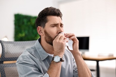 Photo of Sick man with runny nose in office