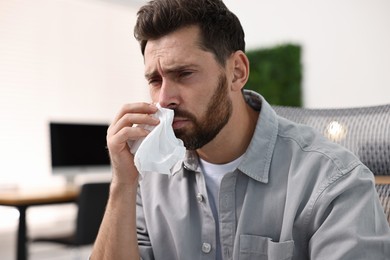 Photo of Sick man with runny nose in office